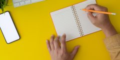 Top view of a man working on his project by writing on notebook