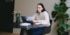 Young woman typing on laptop whilst sat at a desk.