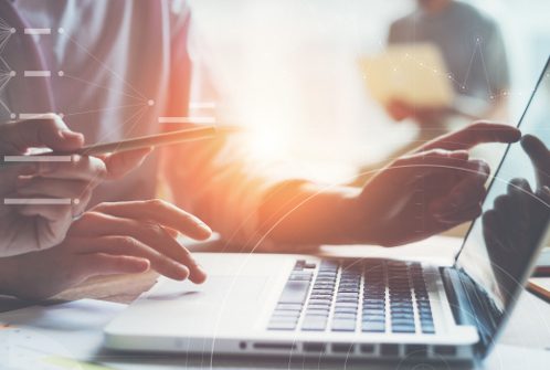 Someone typing on a laptop with sunshine in the background