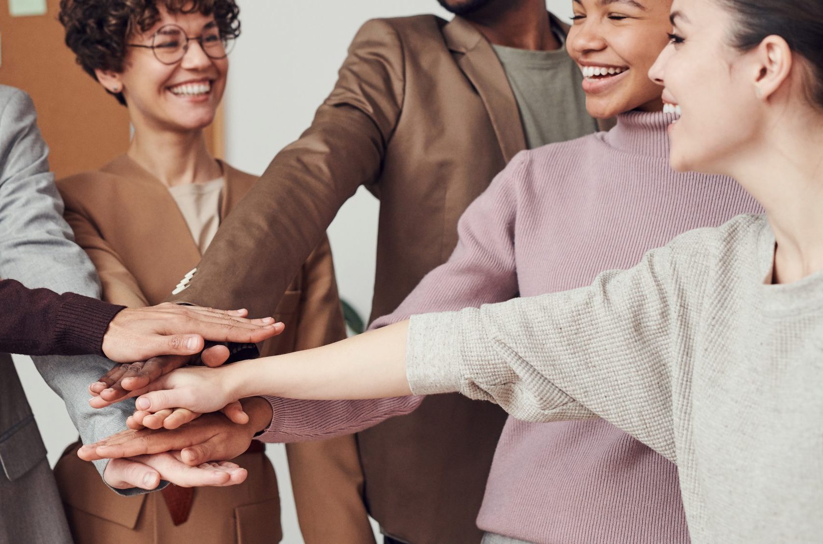 A group of people putting hands into a circle and smiling
