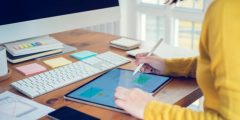 person working on a tablet surrounded by office supplies