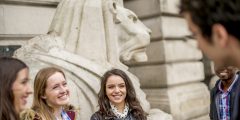 Four students standing in front of one of the lions in Market Square in Nottingham