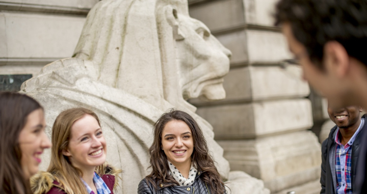 Four students standing in front of one of the lions in Market Square in Nottingham