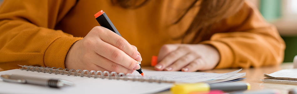 College student in class, taking notes and using a highlighter
