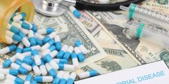 A picture of capsules, syringes and a stethoscope lying on dollar bills together with a note mitochondrial disease written on a pad.