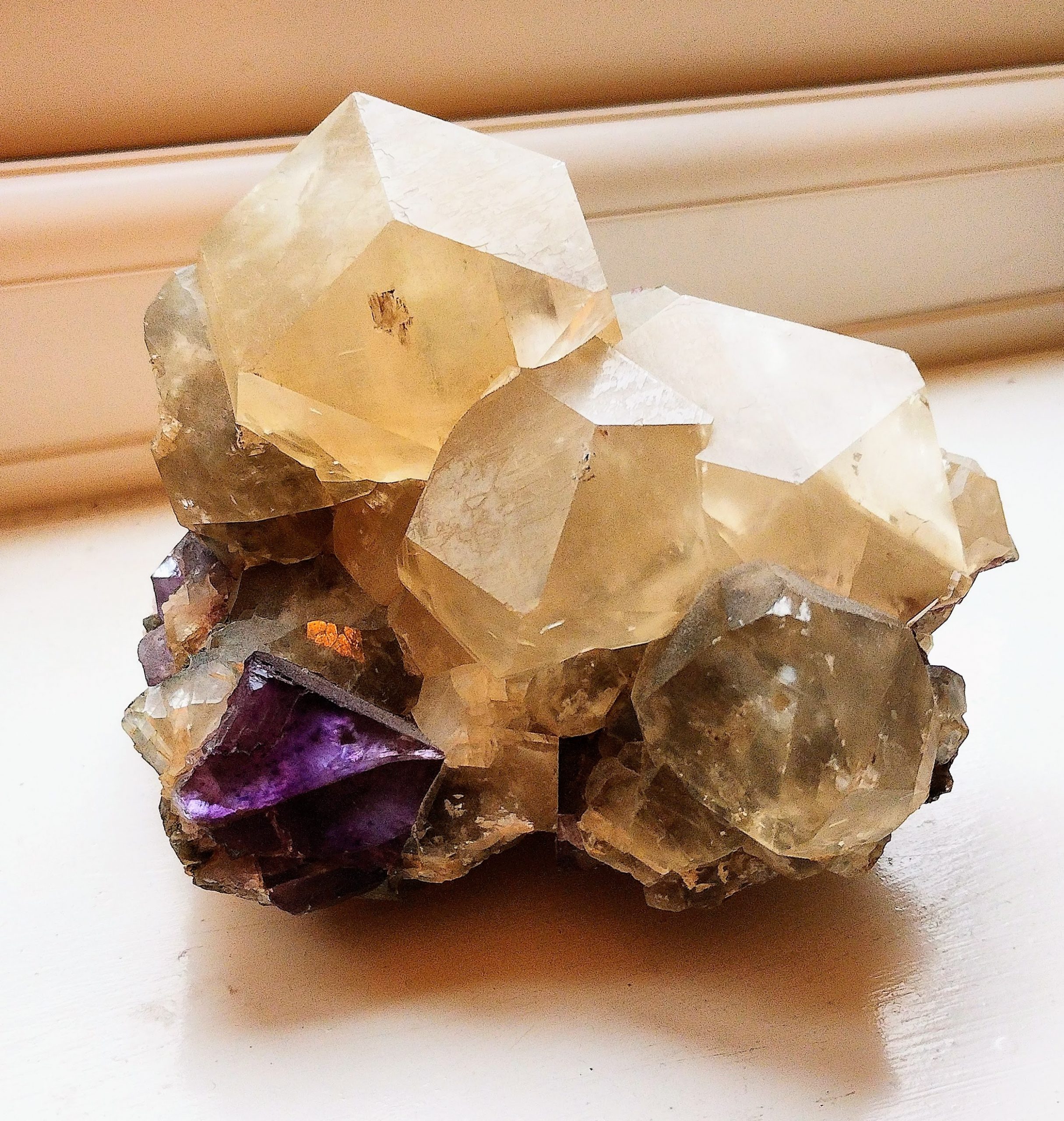 lots of large quartz crystals in a pile with an amethyst crystal at the bottom
