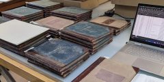 Piles of bound volumes and archive boxes on a table