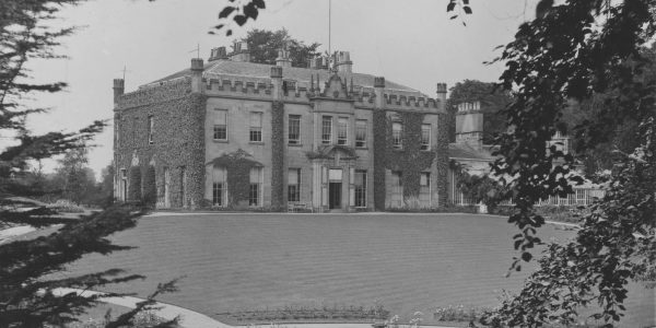 Black and white photograph of a country house and its garden.