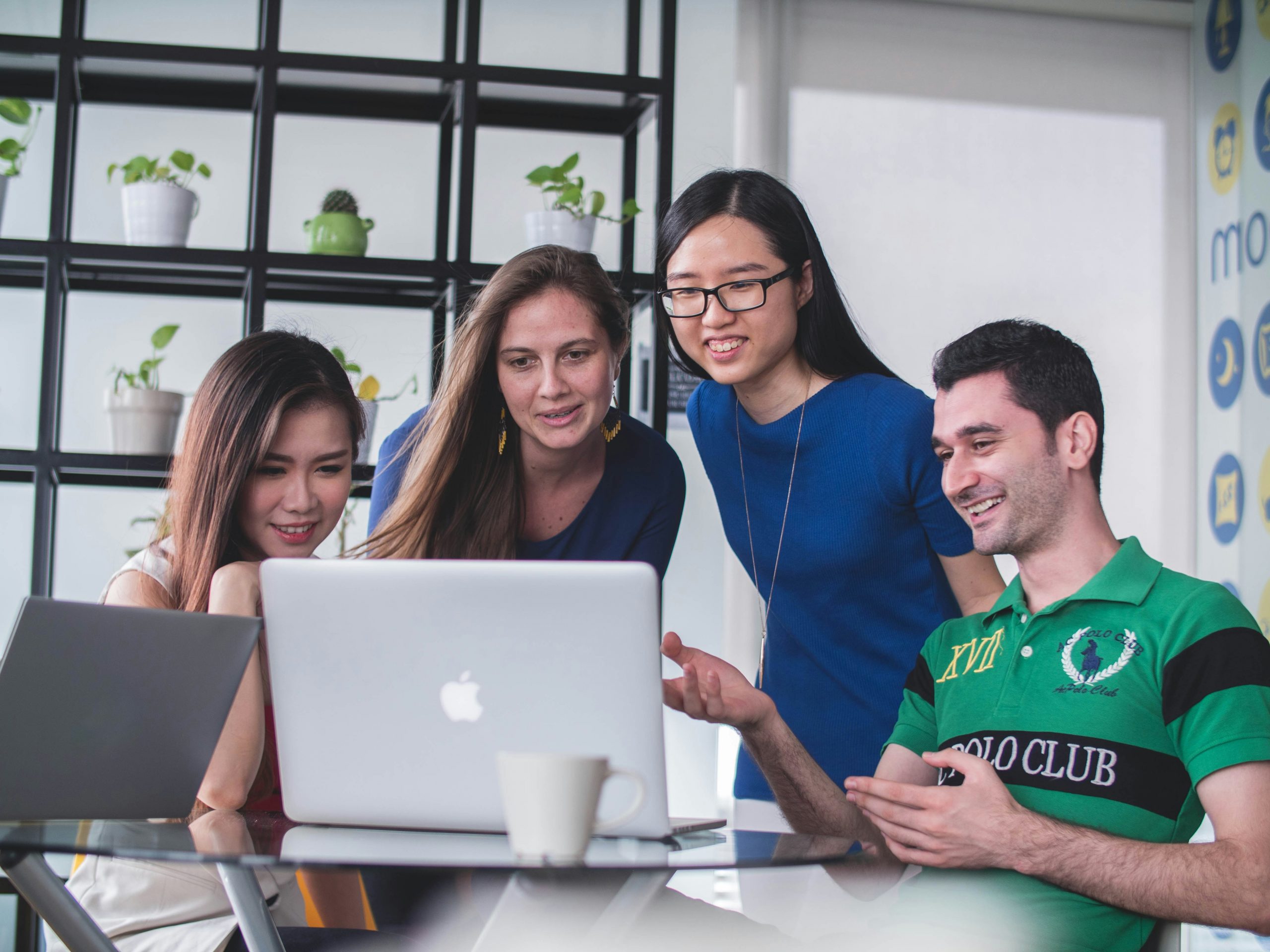 A group of four international students looking at a laptop
