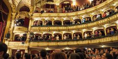 A theatre full of people giving a standing ovation to a performance.